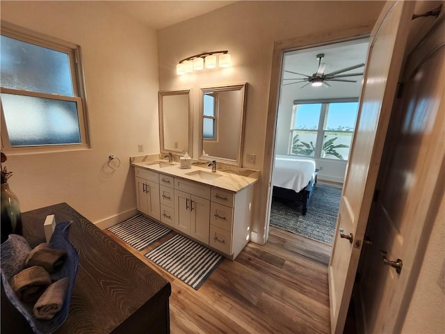 full bathroom featuring a ceiling fan, double vanity, a sink, and wood finished floors