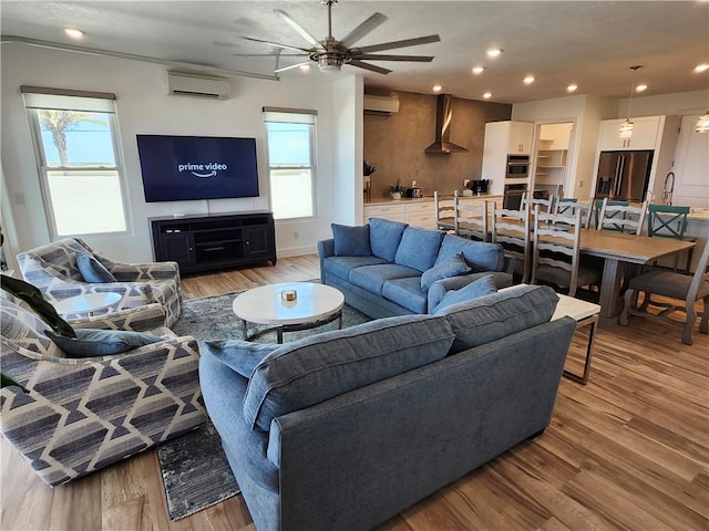 living room featuring light wood finished floors, recessed lighting, ceiling fan, a wall mounted air conditioner, and a wall mounted AC