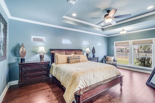 bedroom featuring baseboards, a raised ceiling, wood finished floors, and crown molding