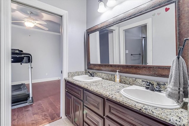 full bathroom featuring a sink, double vanity, wood finished floors, and crown molding