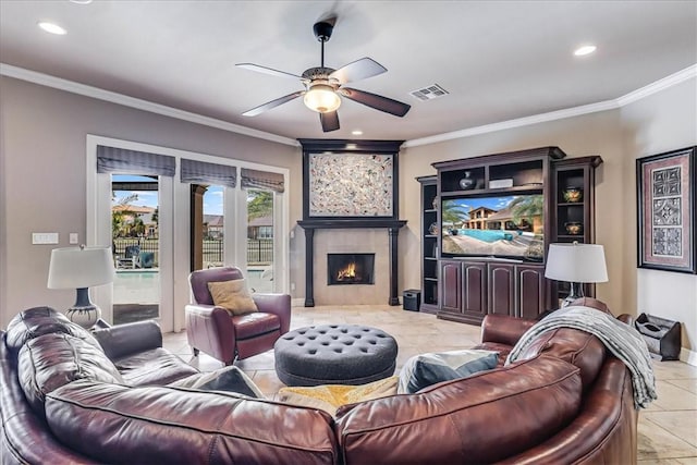 living room featuring a ceiling fan, baseboards, visible vents, a fireplace, and ornamental molding