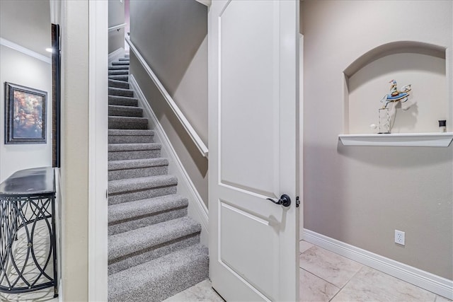 stairway featuring marble finish floor and baseboards