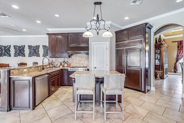 kitchen featuring visible vents, a peninsula, a sink, stainless steel appliances, and a kitchen breakfast bar