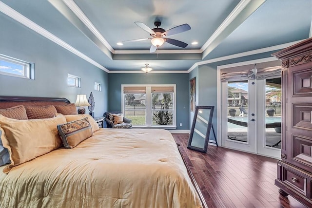 bedroom with access to exterior, dark wood-style floors, multiple windows, and a tray ceiling