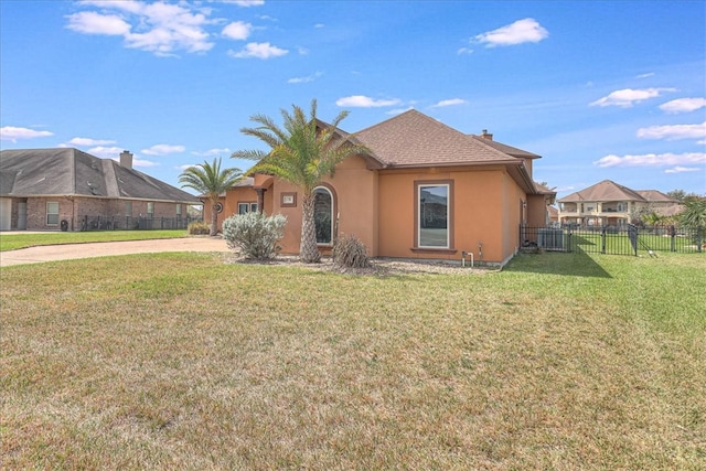 view of front of home with stucco siding, driveway, a front yard, and fence