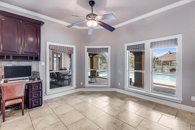 unfurnished office featuring a ceiling fan, baseboards, and ornamental molding