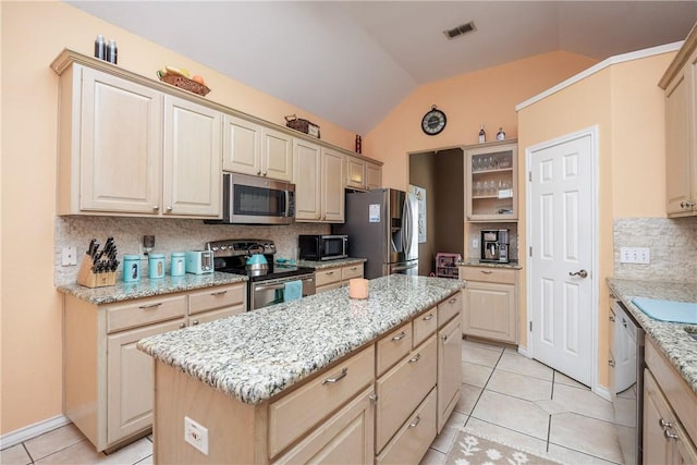 kitchen with stainless steel appliances, a kitchen island, visible vents, vaulted ceiling, and tasteful backsplash