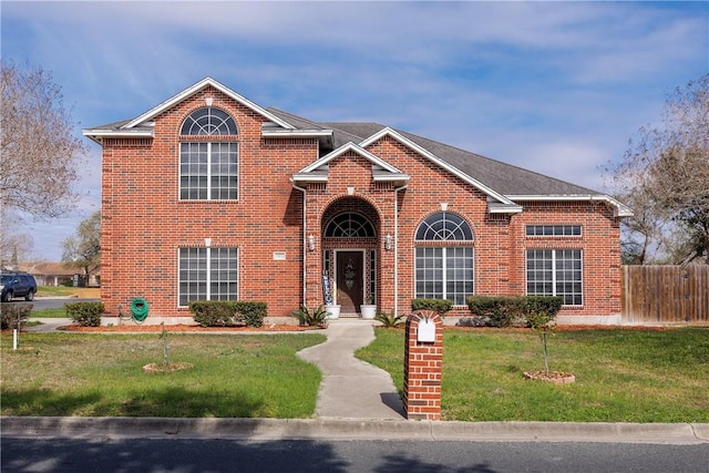 traditional home featuring brick siding, fence, and a front lawn