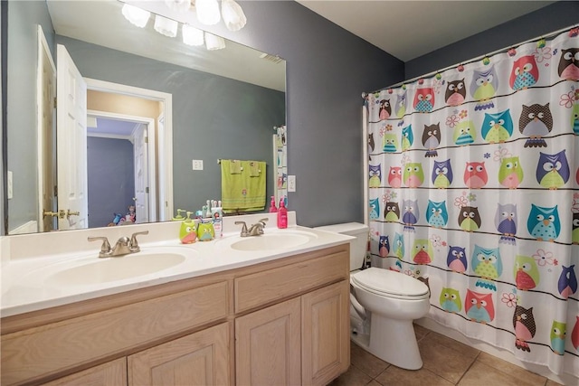 bathroom with double vanity, toilet, a sink, and tile patterned floors