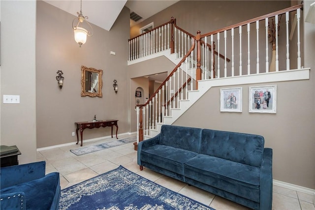 tiled living room with a high ceiling, stairway, visible vents, and baseboards