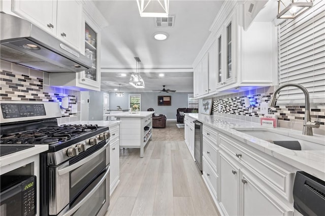 kitchen featuring white cabinets, range with two ovens, sink, light hardwood / wood-style flooring, and ceiling fan