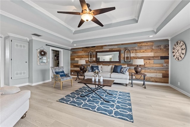 living room with ceiling fan, wood walls, wood-type flooring, and a tray ceiling