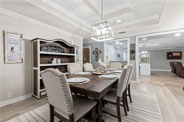 dining room with a raised ceiling, crown molding, and light hardwood / wood-style flooring