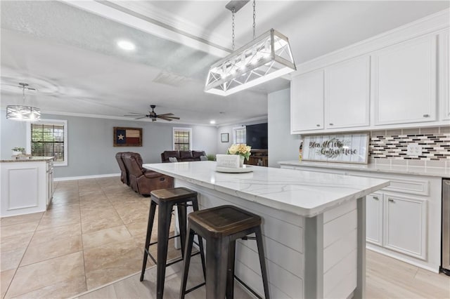 kitchen with white cabinetry, ceiling fan, crown molding, decorative light fixtures, and a kitchen island