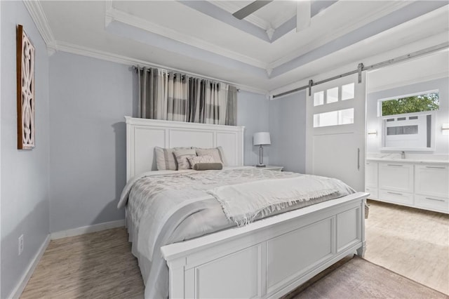 bedroom with a tray ceiling, ceiling fan, crown molding, a barn door, and hardwood / wood-style flooring