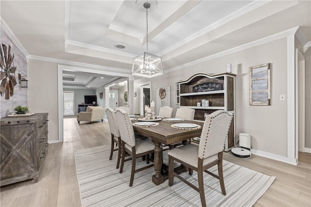 dining room featuring light hardwood / wood-style floors, a raised ceiling, and crown molding