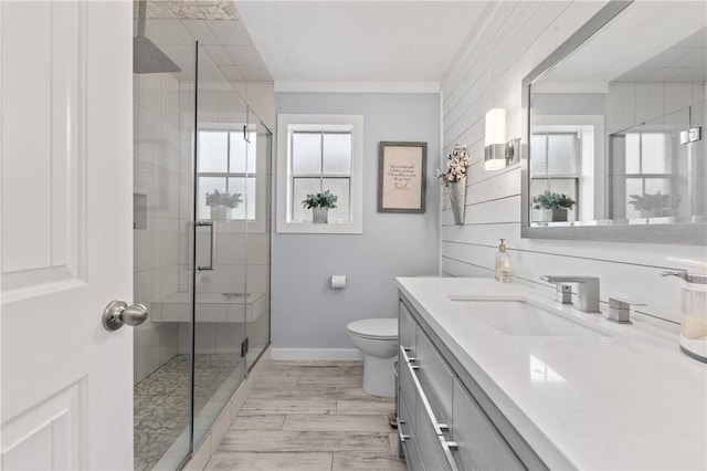 bathroom featuring hardwood / wood-style floors, toilet, vanity, a shower with shower door, and ornamental molding