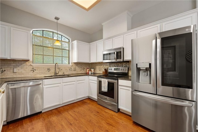 4442 Lake Superior Dr, Corpus Christi, TX 78413 - kitchen with stainless steel appliances, a sink, light wood finished floors, white cabinets, and tasteful backsplash