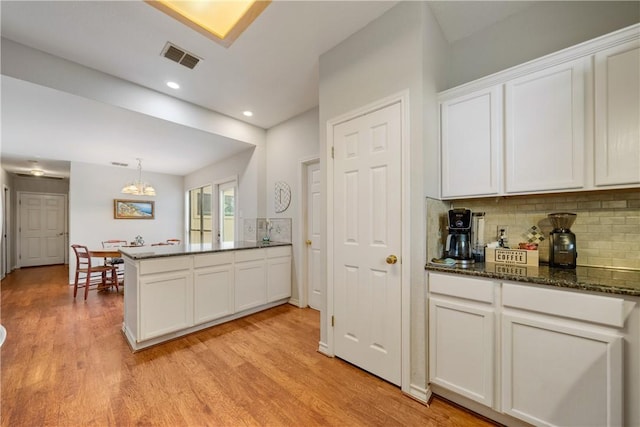 4442 Lake Superior Dr, Corpus Christi, TX 78413 - kitchen with a peninsula, tasteful backsplash, light wood finished floors, white cabinetry, and a chandelier
