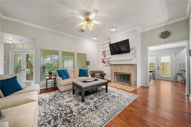 4442 Lake Superior Dr, Corpus Christi, TX 78413 - living room featuring a ceiling fan, wood finished floors, crown molding, a tiled fireplace, and built in shelves