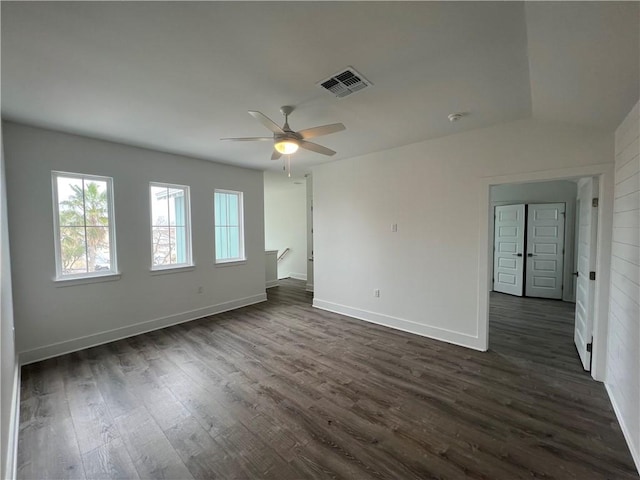 spare room featuring visible vents, baseboards, dark wood-type flooring, and ceiling fan