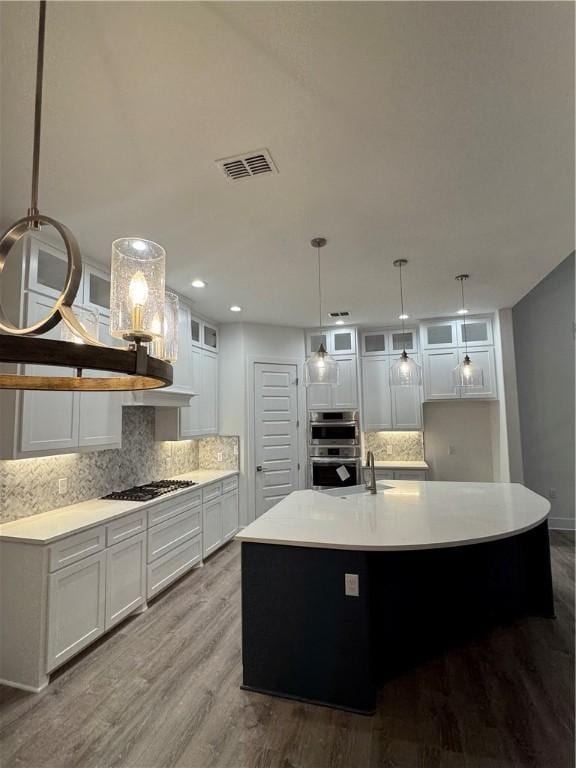 13741 Tajamar St, Corpus Christi, TX 78418 - kitchen with decorative backsplash, white cabinets, wood finished floors, an island with sink, and light countertops