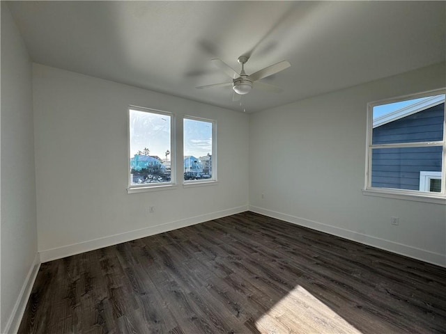 unfurnished room with baseboards, dark wood-style floors, and a ceiling fan