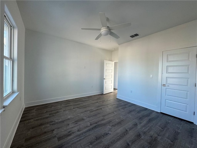 spare room with visible vents, baseboards, ceiling fan, and dark wood-style flooring