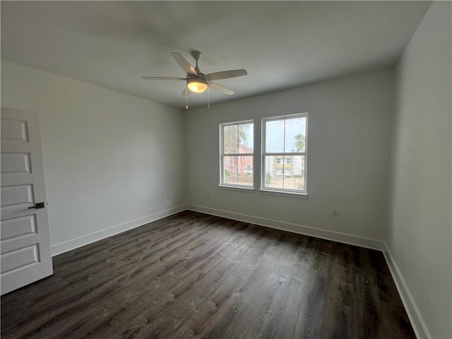 unfurnished room with baseboards, dark wood-style flooring, and ceiling fan