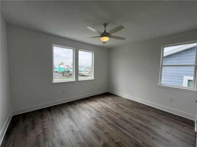 spare room with dark wood finished floors, a ceiling fan, and baseboards