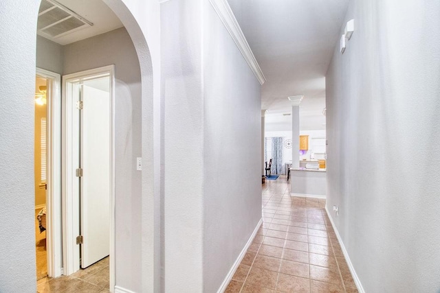 corridor with ornamental molding and light tile patterned flooring