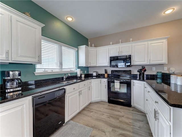 kitchen featuring white cabinetry, light hardwood / wood-style floors, dark stone counters, black appliances, and sink