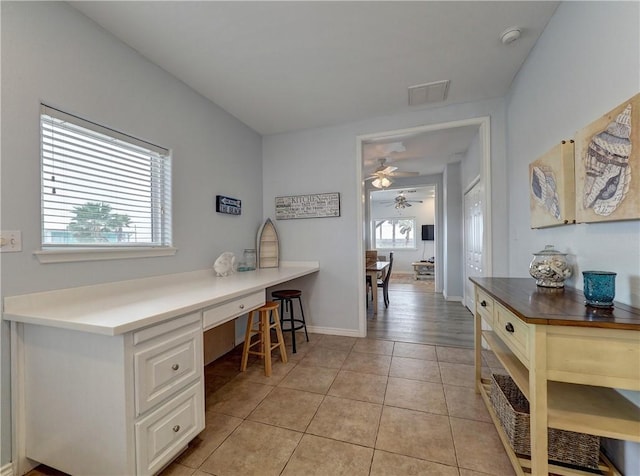 tiled office space with ceiling fan, built in desk, and a healthy amount of sunlight