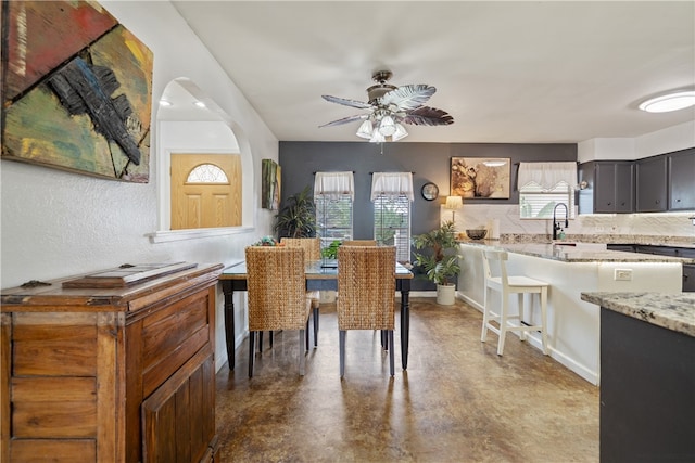 dining space with ceiling fan, sink, and concrete floors