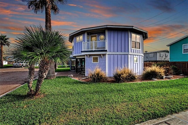 view of front of property featuring a lawn and a balcony