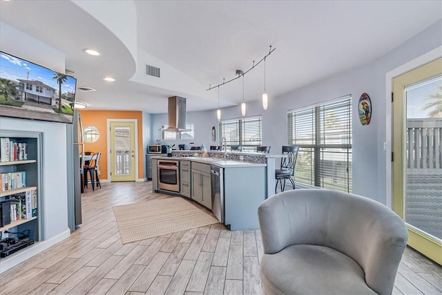 kitchen with decorative light fixtures, light hardwood / wood-style floors, and island exhaust hood