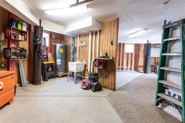 basement with electric water heater, sink, and wood walls