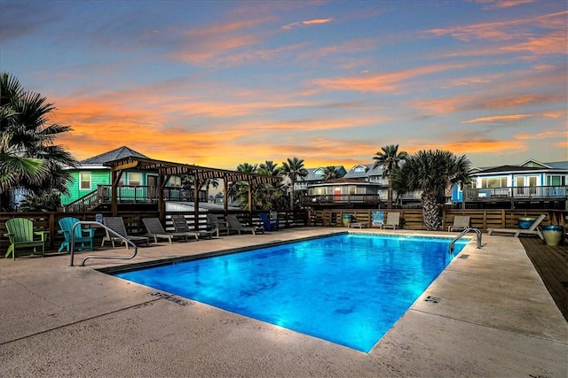 pool at dusk featuring a patio