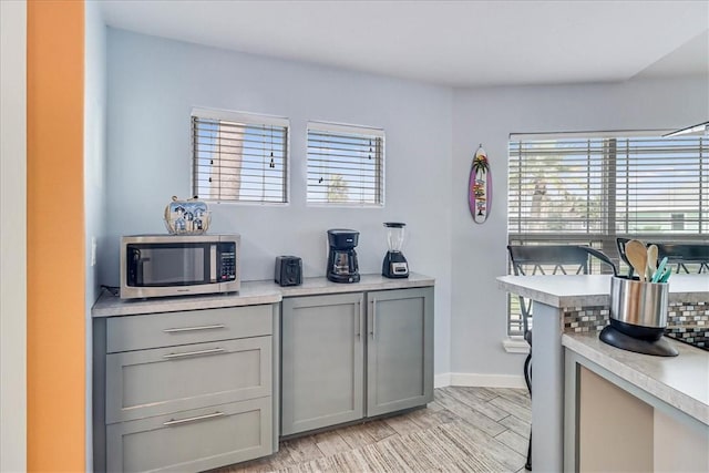 kitchen with gray cabinetry, plenty of natural light, and light hardwood / wood-style flooring