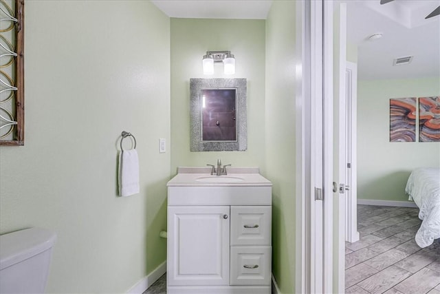 bathroom featuring vanity, hardwood / wood-style flooring, and toilet