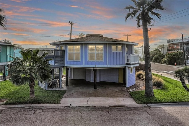 coastal home featuring a balcony, a garage, and a carport