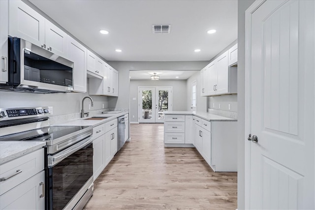 kitchen featuring white cabinets, sink, light wood-type flooring, and appliances with stainless steel finishes