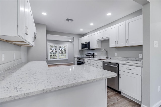 kitchen with stainless steel appliances, white cabinetry, sink, and kitchen peninsula