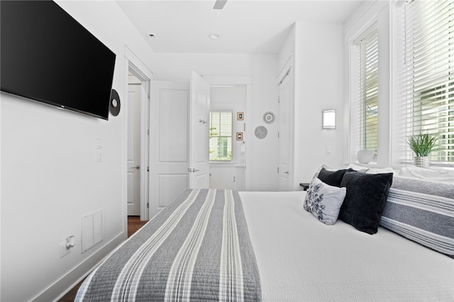 bedroom with a ceiling fan, visible vents, dark wood finished floors, and baseboards