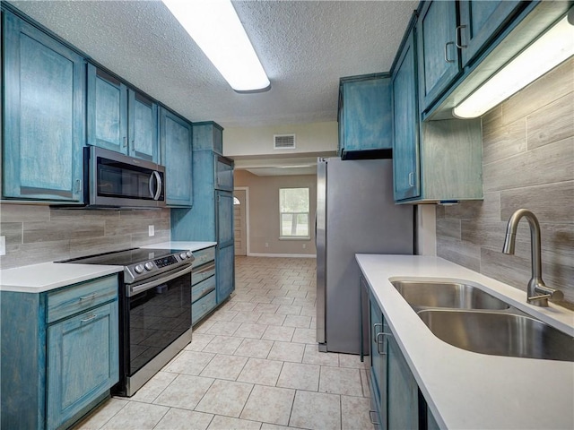 2746 Beaumont Ave, Ingleside, TX 78362 - kitchen with appliances with stainless steel finishes, a sink, tasteful backsplash, a textured ceiling, and light tile patterned floors