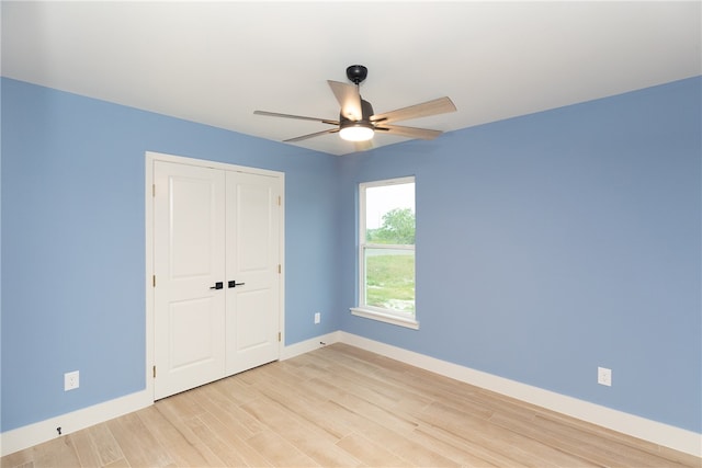 unfurnished bedroom with light wood-type flooring, ceiling fan, and a closet