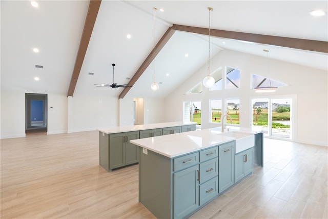 kitchen with high vaulted ceiling, hanging light fixtures, sink, and a kitchen island with sink