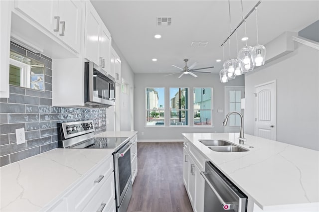 kitchen with stainless steel appliances, decorative light fixtures, dark hardwood / wood-style floors, light stone countertops, and sink