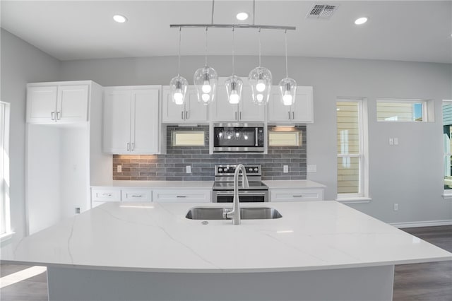 kitchen featuring light stone counters, a center island with sink, stainless steel appliances, white cabinetry, and pendant lighting