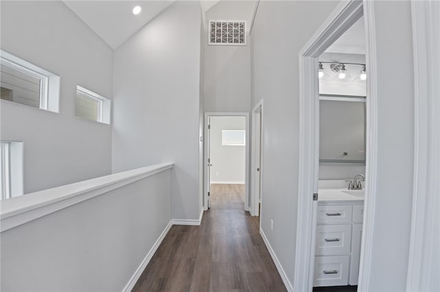 hall featuring dark wood-type flooring, sink, and vaulted ceiling